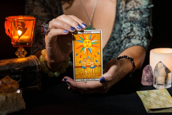 Güneşin tarot kartını gösteren bir kadının ellerinin ayrıntıları. Tarot kartlı kehanet oturumu kavramı.