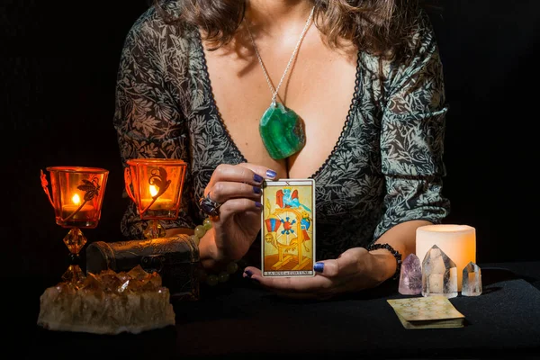Detail of a woman\'s hands showing the tarot card of the roulette of fortune. Concept of a fortune telling session with tarot cards.