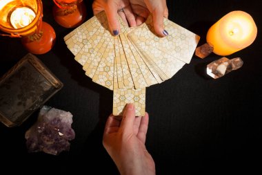Başka bir el desteden kart alırken bir kadının ellerinin tarot kartlarını göstermesinin detayları. Tarot kartlı kehanet oturumu. Yukarıdan görüntüle.