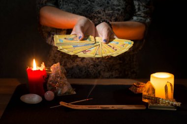 Kehanet sırasında tütsü dumanıyla tarot kartlarını temizleyen bir kadının elleri. Tarot kartlı kehanet oturumu kavramı.