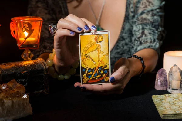 Ölüm tarot kartını gösteren bir kadının ellerinin ayrıntıları. Tarot kartlı kehanet oturumu kavramı.