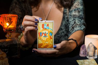 Kader ruletinin tarot kartını gösteren bir kadının ellerinin ayrıntıları. Tarot kartlarıyla falcılık oturumu kavramı.