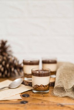 Beyaz arka planlı, tahta bir tahtanın üzerinde kristal bir bardakta sunulan kremalı kekin hayatı. Kopyalanacak alan.