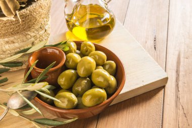 Bir kase zeytinle sakin bir hayat, farklı baharatlarla süslenmiş, ahşap bir tahtada. Ev yapımı zeytin, geleneksel Akdeniz mutfağı..