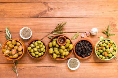 Değişik zeytin çeşitleriyle dolu bir hayat, tahta tahtalardaki kaselerde sunuluyor, farklı geleneksel sargılarla tatlandırılmış. Geleneksel ev yapımı sargı, tipik Akdeniz mutfağı..