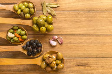 Değişik zeytin çeşitleriyle dolu, ahşap kepçelerle sunulmuş, farklı geleneksel soslarla tatlandırılmış bir hayat. Geleneksel ev yapımı pansuman, tipik Akdeniz mutfağı. Üst görünüm.