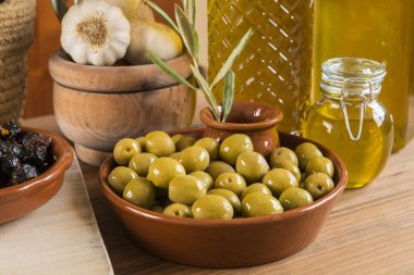 Geleneksel şekilde çeşnili farklı zeytin çeşitleri olan, tahta tahtalar üzerinde kâselerle sunulan, ve birkaç cam şişe içinde ekstra saf zeytinyağı içeren bir hayat..