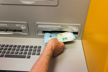 Arahal, Sevilla, İspanya. 25 Mayıs 2022. Yaşlı bir kadının ATM 'den para çekmesinin ayrıntıları. Bazı yaşlı insanlar ATM kullanmakta zorlanıyor.
