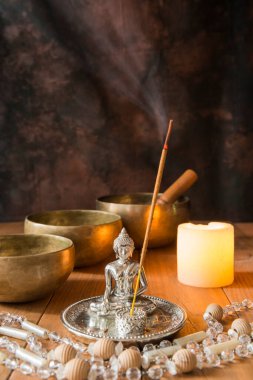Tibet kâseleriyle, boncuk kolye, mum, tütsü ve tahta tahtada bir Buda figürüyle dolu bir hayat. Meditasyon ve müzik terapisi için mum ışığında sunak..