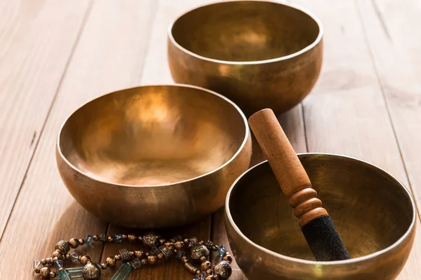 Tahta bir masanın üzerinde üç bronz Tibet kasesi olan bir hayat. Şarkı kaseleri meditasyon ve müzik terapisi seanslarında kullanılıyor..
