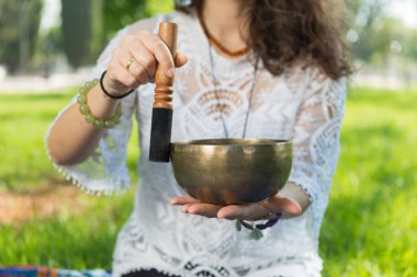 Park alanında meditasyon ve müzik terapisi sırasında bir kadının elini tutup Tibet şarkı kasesi çalması..