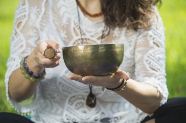 Park alanında meditasyon ve müzik terapisi sırasında bir kadının elini tutup Tibet şarkı kasesi çalması..