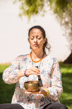 Meditasyon ve müzik terapisi sırasında Tibet şarkı kasesi çalan bir kadın..