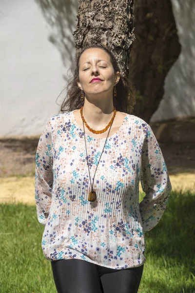 A woman sunbathes standing and hugging a tree. Hugging a tree has many health benefits.