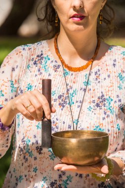 Park alanında meditasyon ve müzik terapisi sırasında bir kadının elini tutup Tibet şarkı kasesi çalması..