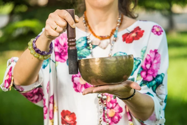 Park alanında meditasyon ve müzik terapisi sırasında bir kadının elini tutup Tibet şarkı kasesi çalması..