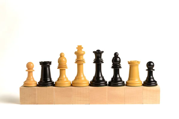 White and black chess pieces on wooden blocks with white background. Concept of teamwork and cooperation.