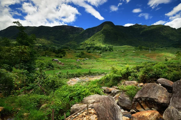 Berlawanan dengan latar belakang pegunungan hijau tinggi adalah sebuah villag kecil — Stok Foto