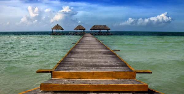 Yellow pier stretching into the ocean to Daybeds — Stock Photo, Image