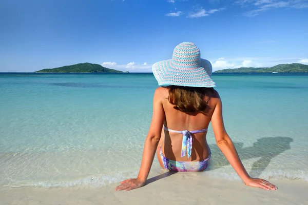 A girl in a summer hat lying on the sand and look at the sky on — Stock Photo, Image