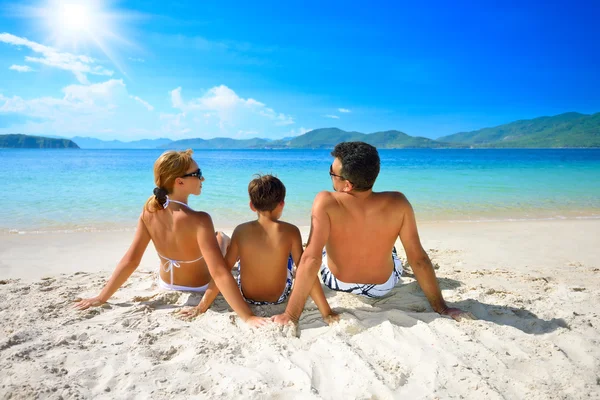 Glückliche Familie sonnt sich am Strand vor dem Hintergrund der Insel Stockbild