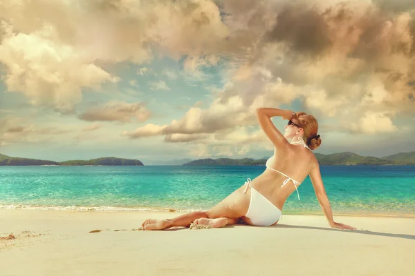 Schöne Frau entspannt sich an einem sonnigen weißen Sandstrand. — Stockfoto