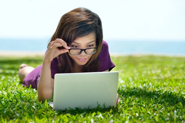 Foto van lachende Aziatische student werkt aan een laptop in de buitenlucht — Stockfoto
