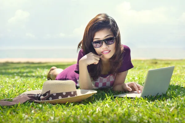 Bastante joven asiático mujer es soñando con un portátil mintiendo en la —  Fotos de Stock