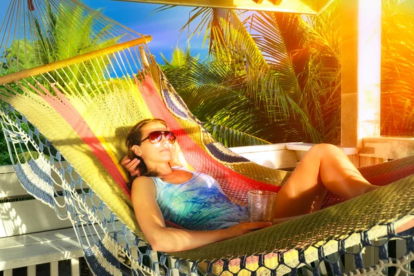 Bella donna si rilassa su un'amaca in un bungalow tropicale — Foto Stock