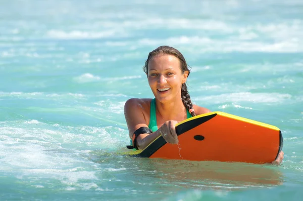 Jovem mulher atraente bodyboards na prancha de surf com sorriso agradável — Fotografia de Stock