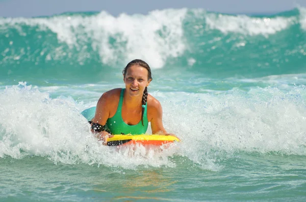 Joven mujer atractiva bodyboards en tabla de surf con una sonrisa agradable —  Fotos de Stock