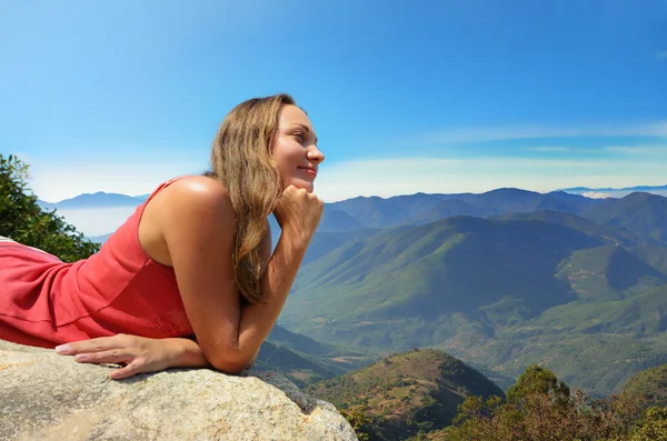 Fiatal nő nézett a hegyek, a szélén egy sziklán — Stock Fotó