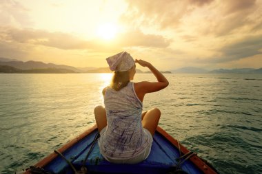 Woman traveling by boat at sunset among the islands clipart