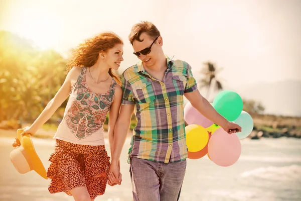 Casal andando na praia com bolas coloridas de ar . — Fotografia de Stock