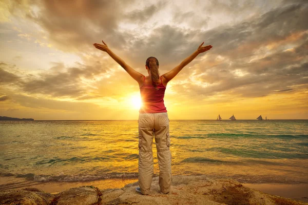 Young woman with raised hands standing on shore and looking to a — Stock Photo, Image