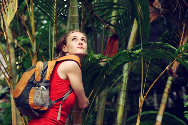 Young tourist with backpack walking in tropical forest — Stock Photo, Image