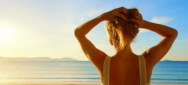 Una vista hacia atrás en una maravillosa mujer joven mirando al mar y —  Fotos de Stock