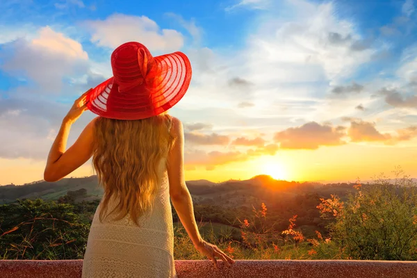 Uma visão traseira em uma jovem mulher maravilhosa assistindo por do sol . — Fotografia de Stock