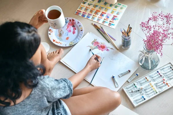 Mujer artista pinta y bebe té Imagen de archivo