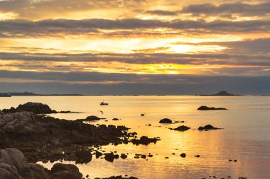 San Vicente of O Grove rocky coast at golden and cloudy sunset