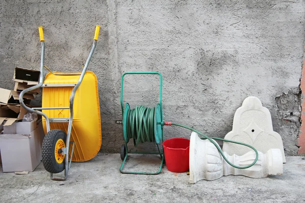 Wheelbarrow, hose and cartons — Stock Photo, Image