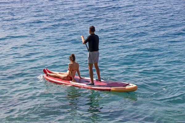 年轻夫妇在暑假时一起站在船舷上冲浪 — 图库照片