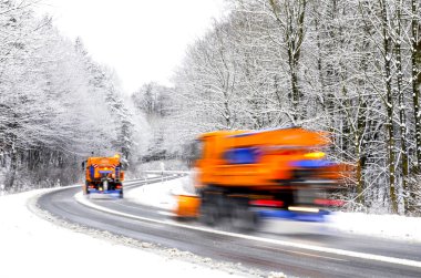 Snow plows on winter road, vehicles blurred clipart