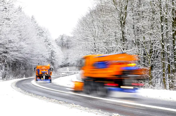 Arados de nieve en el camino de invierno, vehículos borrosos —  Fotos de Stock