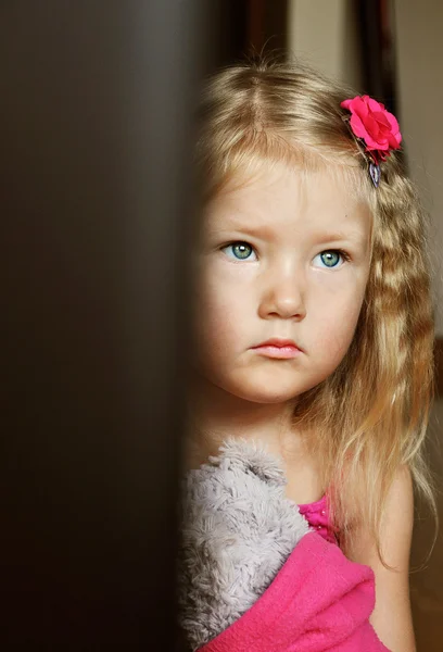 Sad little girl sitting with a teddy bear in hand — Stock Photo, Image