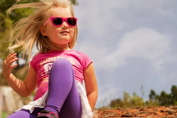 Meisje zit in roze bril en kijkt naar de afstand — Stockfoto