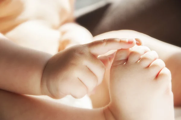 Baby houdt zijn been hand — Stockfoto