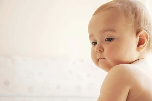 Baby zittend op het bed en kijkt — Stockfoto