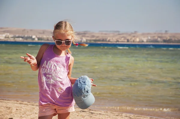 Fille se tient près de la mer souriant et tenant un chapeau — Photo