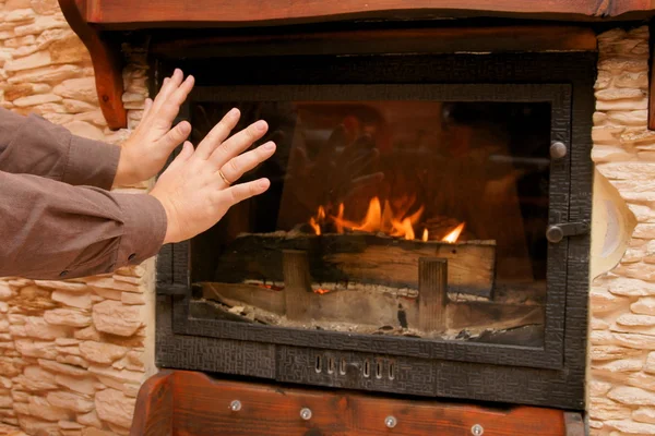 Man warms up by the fire / fireplace — Stock Photo, Image